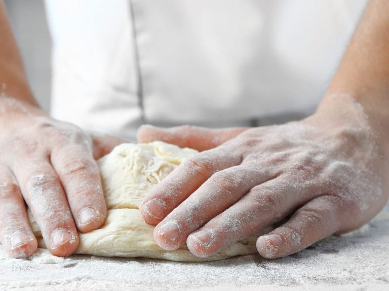Manos amasando masa en una superficie enharinada.
